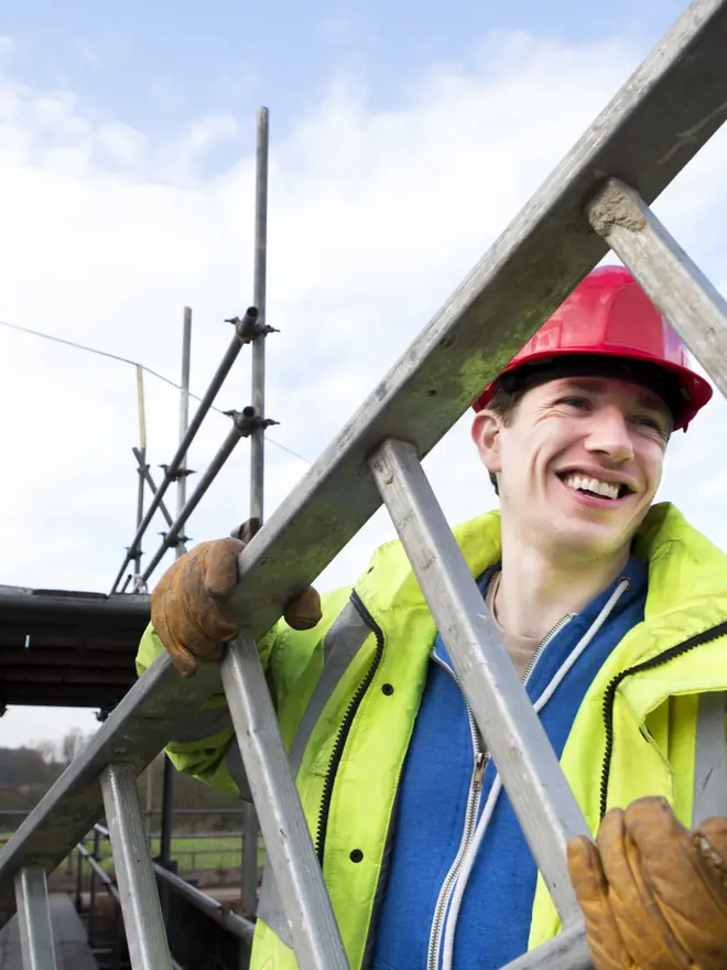 Roofer carrying a ladder on scaffolding