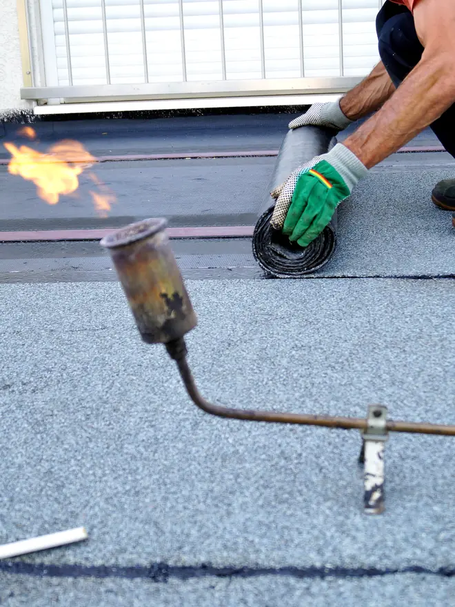 Roofer sealing torch-on felt on a flat roof