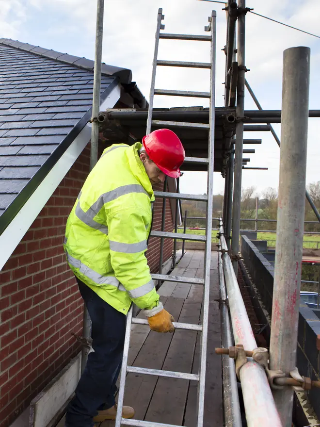 Roofer on scaffolding beside a new slate roof